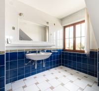 A bathroom in a family house with blue and white tiles and a large window.