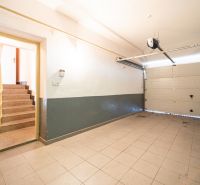 A garage in a family house with an open gate and stairs to the interior.