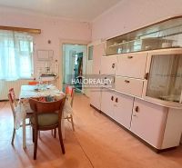 Dining room in a family house with retro furniture, a floral tablecloth, and a display cabinet.