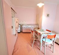 Pink kitchen with dining table and bed in a family house.