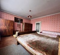 Spálňa v rodinnom dome s dreveným dekorom, starožitným nábytkom a ružovými tapetami.