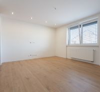 Interior of a family house with a wooden decor floor, white walls, and a window.