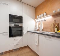 A kitchen in a family house with white cabinets, a stove, and a wooden-patterned floor.