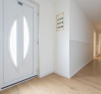 Entrance hallway in a family house with a wooden decor floor and white doors.