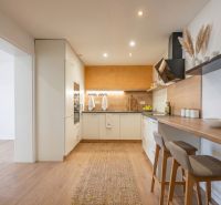 A kitchen in a family house with a bar counter and a wooden decor floor.
