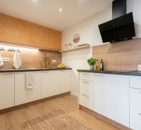 A kitchen in a family house with white cabinets, wooden decor, and citrus fruits on the shelf.