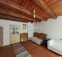 A room with a wooden ceiling, a floor with a wooden decor, and simple furniture.