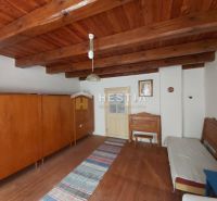 Interior with a wardrobe and a bed, floor with wooden decor, ceiling with wooden beams.