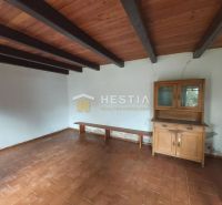 A room with a ceramic floor, a wooden beam ceiling, and a wooden display cabinet. Land - living.