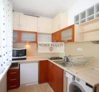 A kitchen in a studio apartment with a microwave, a gas stove, and a wooden decor floor.