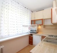 A kitchen with a wooden decor floor and equipment in a studio apartment.