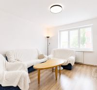 Living room in a two-room apartment with a wooden decor floor, sofas, and a coffee table.