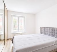 A bedroom with wood-effect flooring and a built-in wardrobe in a 2-room apartment.
