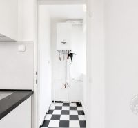 Kitchen area of a 2-room apartment with a black and white floor and a white boiler on the wall.