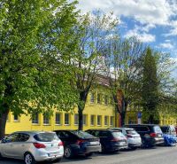 A building on Obrancov mieru Street in Stará Ľubovňa, surrounded by trees and parked cars.
