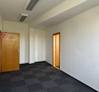 Room with carpet flooring and wooden doors in corporate offices.