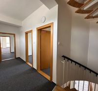 A corridor with a staircase in offices with a wood-decor floor and carpet.
