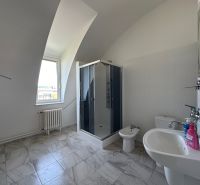 Bathroom with a sink, shower, toilet, and bidet on a tiled floor.