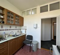A kitchenette with a kitchen counter, open shelves, and appliances in offices.