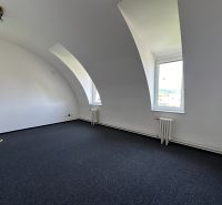 Office space with a curved ceiling and carpet, equipped with a radiator and a window.
