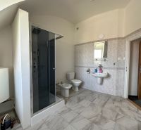 Bathroom with tiles, shower, sink, and toilet in the offices.