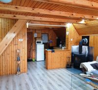 Interior of a cabin with a wood-patterned floor, an armchair, and a fireplace for a cozy atmosphere.