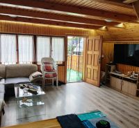 The interior of a cabin with a comfortable couch, television, and a wooden decor floor.
