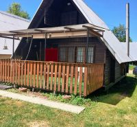 A cottage in Vinné with a wooden terrace and a small yard, surrounded by greenery.