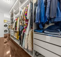A wardrobe in a family house with a wooden decor floor and a washing machine with a dryer.