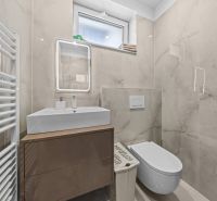 Bathroom in a family house with a sink, toilet, heating, and a mirror with lighting.