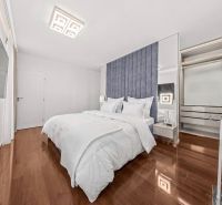 A bright bedroom with a blue headboard, a television, and a wooden decor floor in a family house.