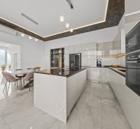 A kitchen in a family house with a marble floor and modern lighting.
