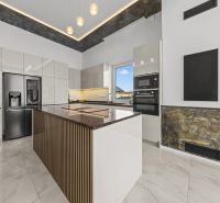 A spacious kitchen in a family house with modern furniture and a stone countertop.