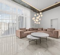 Living room in a family house with a light sofa, round tables, and a pendant light.