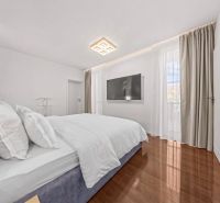 A bright bedroom in a family house with a TV and a wooden decor floor.