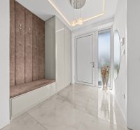 Entrance hallway in a family house with coat racks and comfortable seating on light tiles.