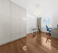 A room in a family house with a piano, a desk, and a wooden-patterned floor.
