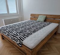A bed with a zebra-patterned blanket in a 2-room apartment, floor with wood decor.