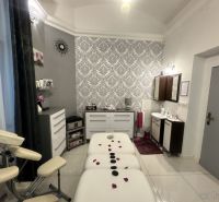 Massage room with a decorated wall, table, and lounger for relaxation treatments.