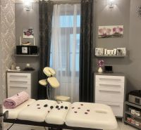 Massage room in commercial premises with a white couch, decorations, and flowers.