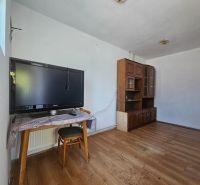A room in a cottage with a TV on the table, a floor with a wooden decor.