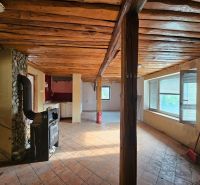 The interior of the cottage with tiled stoves, a wooden ceiling, and large windows.