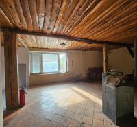 A cottage with a wooden ceiling, a stove, and a window, with a tiled floor.
