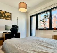 A bedroom in a 2-room apartment with a desk and plants on the windowsill.