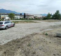 Car on a paved area between industrial buildings and mountains in Martin, Commercial land.