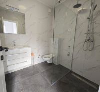 A bathroom in a family house with modern tiles and a shower enclosure.