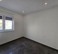 A bright room with a dark floor, white walls, and a window, Family house.
