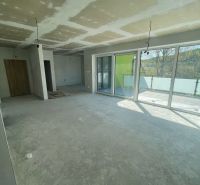 Living room in a three-room apartment with large windows and a concrete floor.