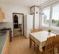 A kitchen in a 3-room apartment with a dining table and a view of greenery.