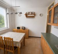 A kitchen in a 3-room apartment with a window, a dining table, and wooden decor furniture.